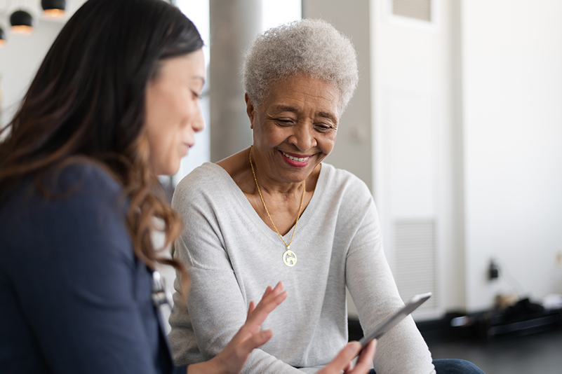 A woman showing a senior something on a phone.